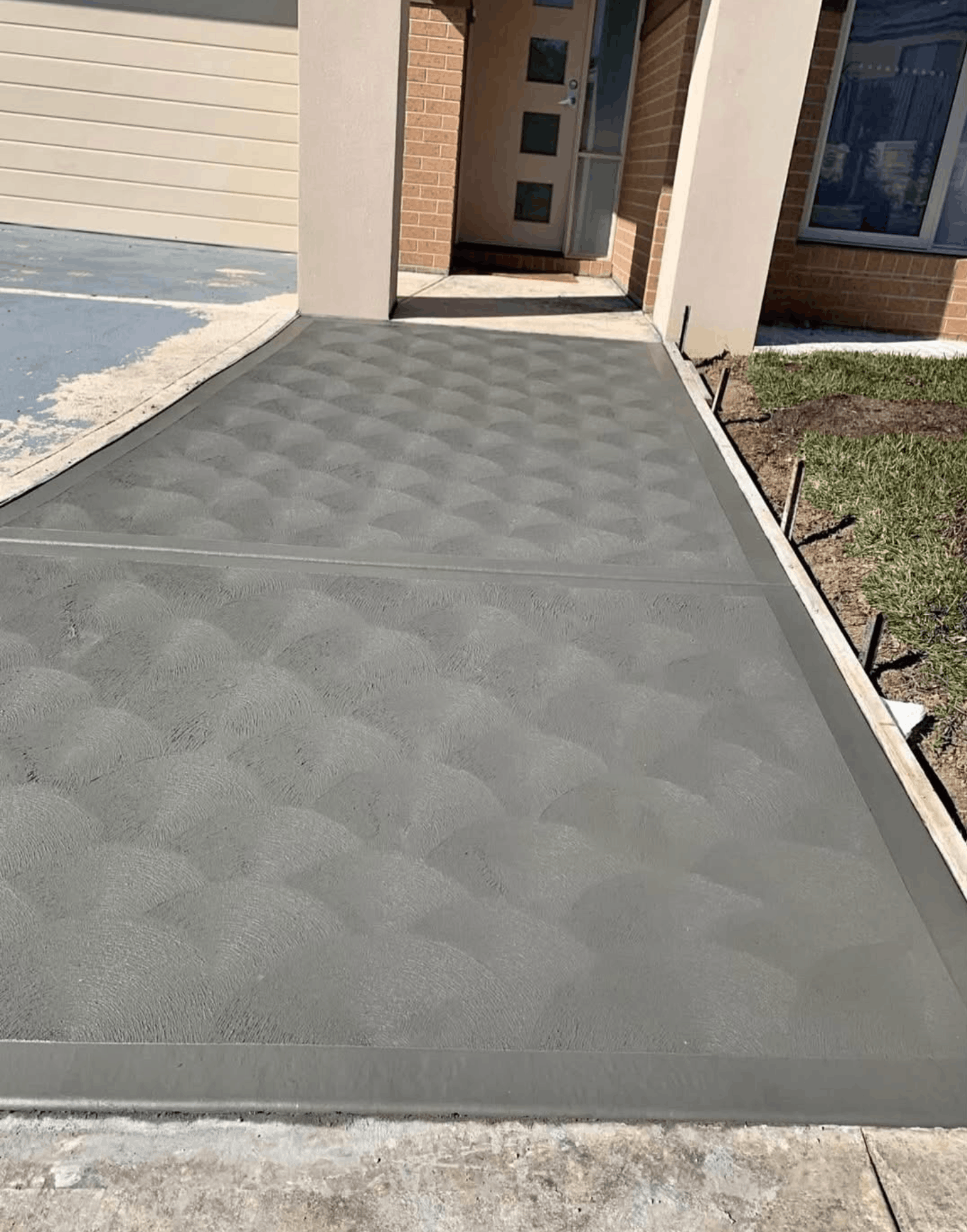 Textured concrete driveway leading to a modern home entry